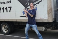 Man in wearing blue t shirt and jeans and standing behind the truck