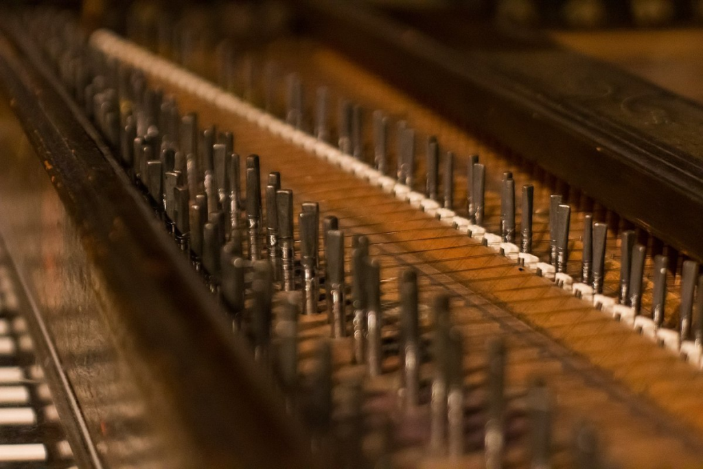 Close-up of piano strings and tuning pins.