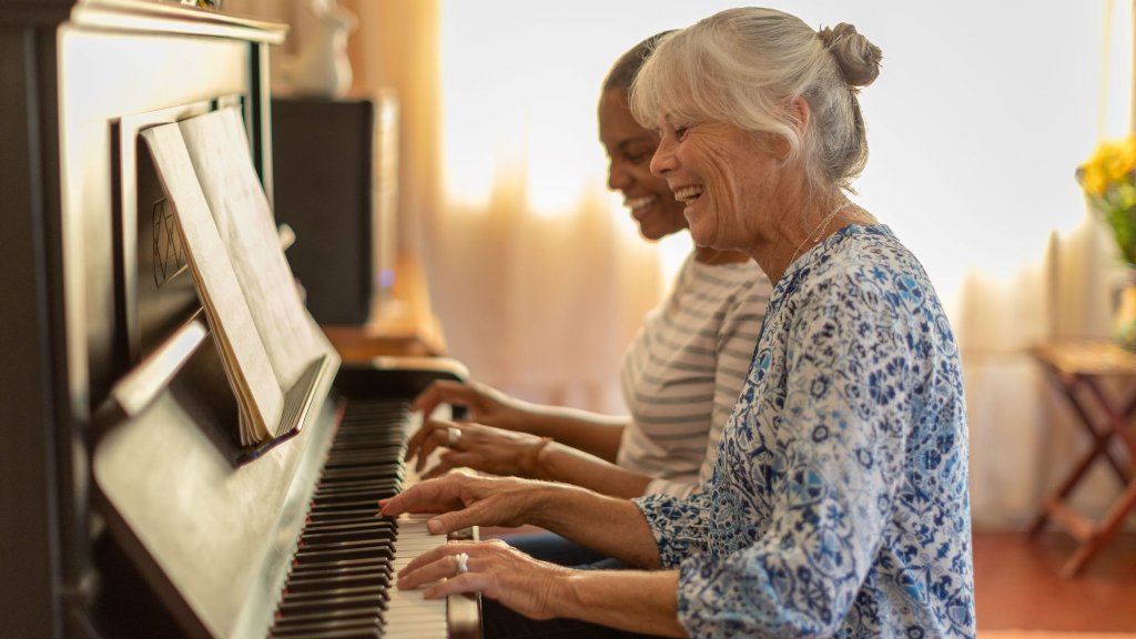 Two women happily playing piano together.