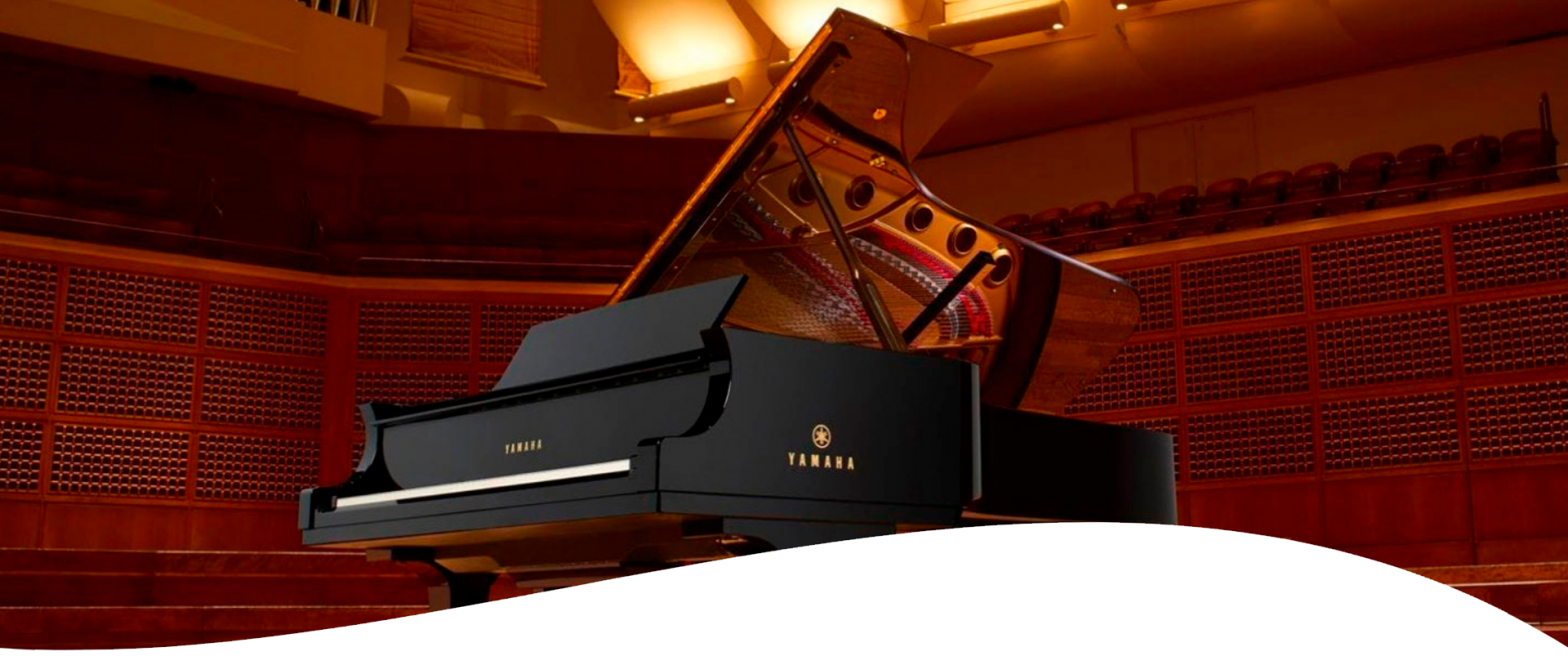 A Yamaha grand piano on a stage with warm lighting.