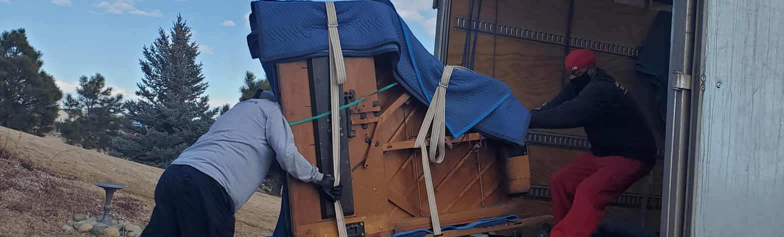 A piano secured with straps and covered by a blue blanket.
