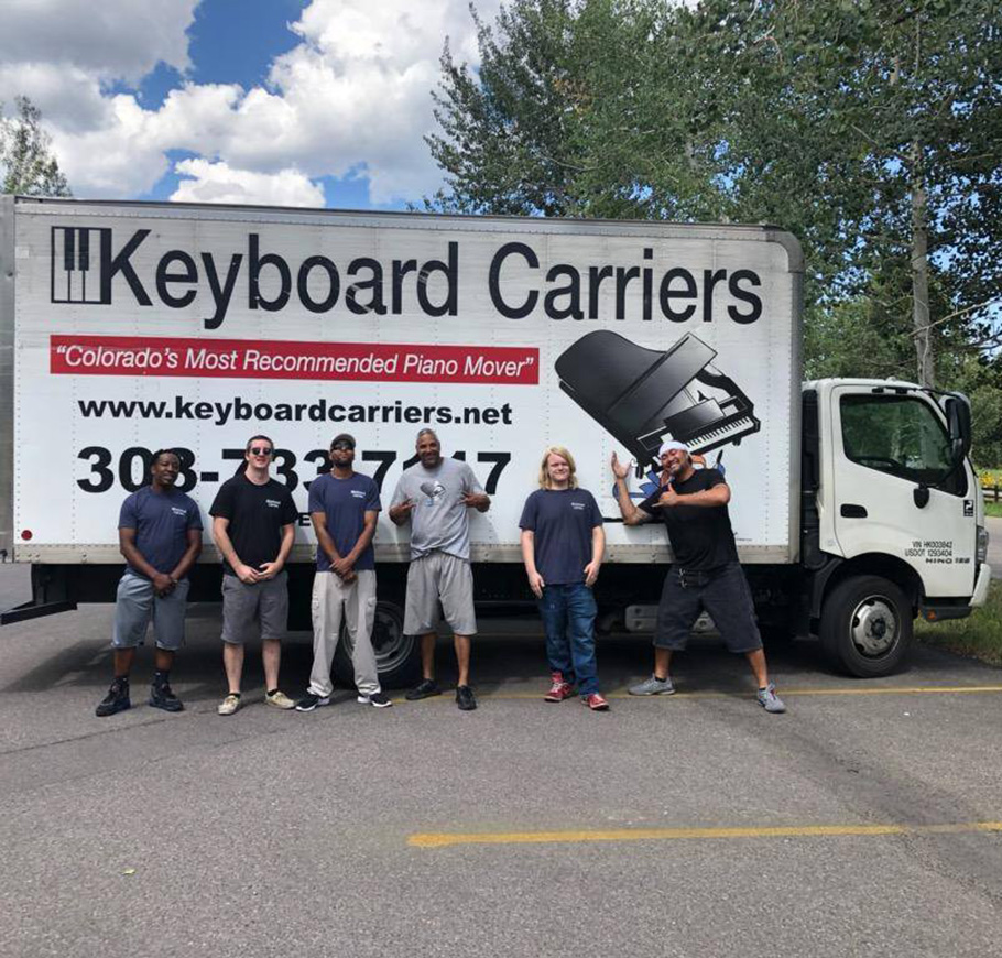 Men standing by a piano moving truck.