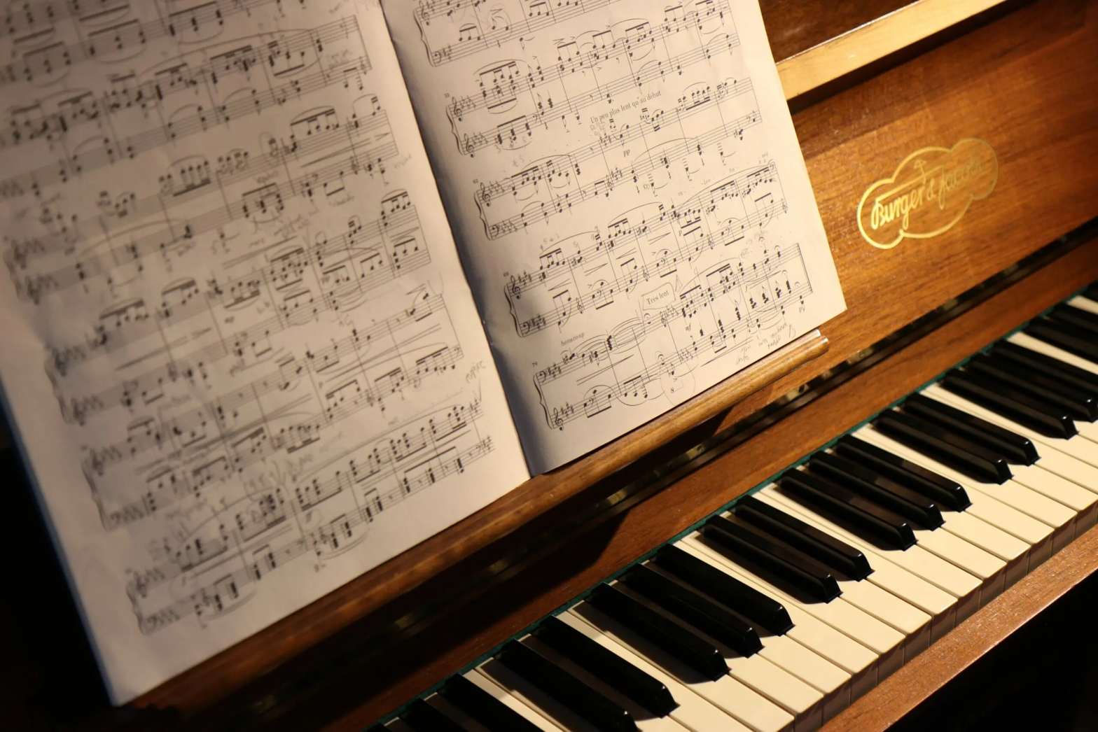 Piano keyboard with open sheet music in warm lighting.