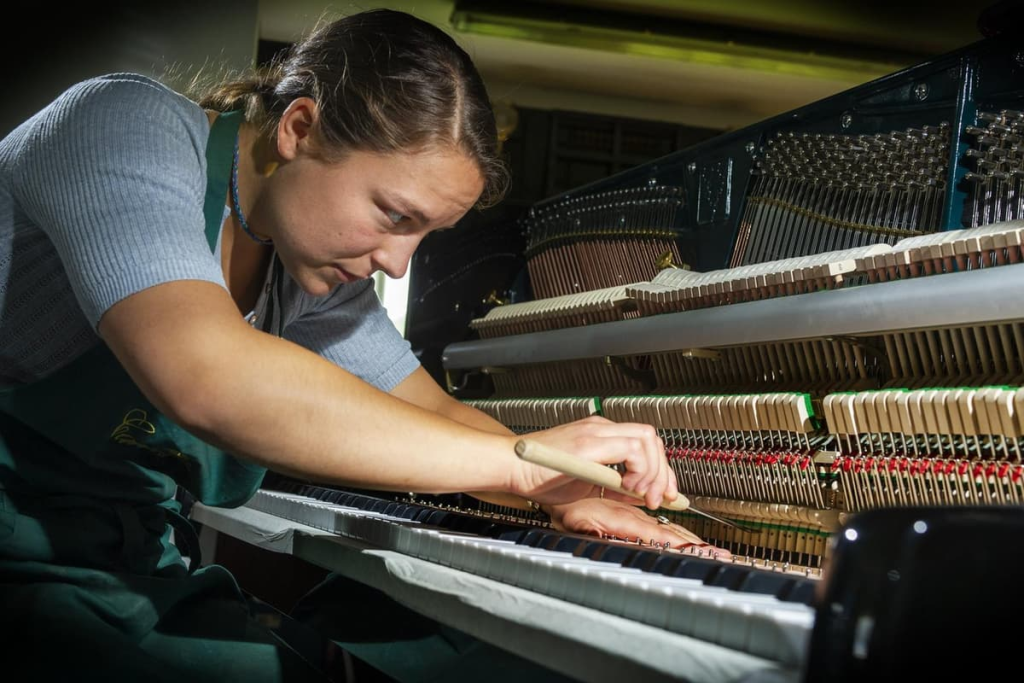Person tuning a piano with tools.