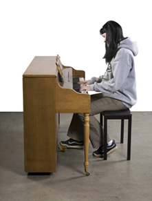 Person playing an upright piano indoors.