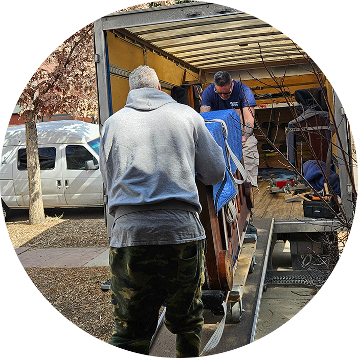 Men loading piano onto a truck ramp.