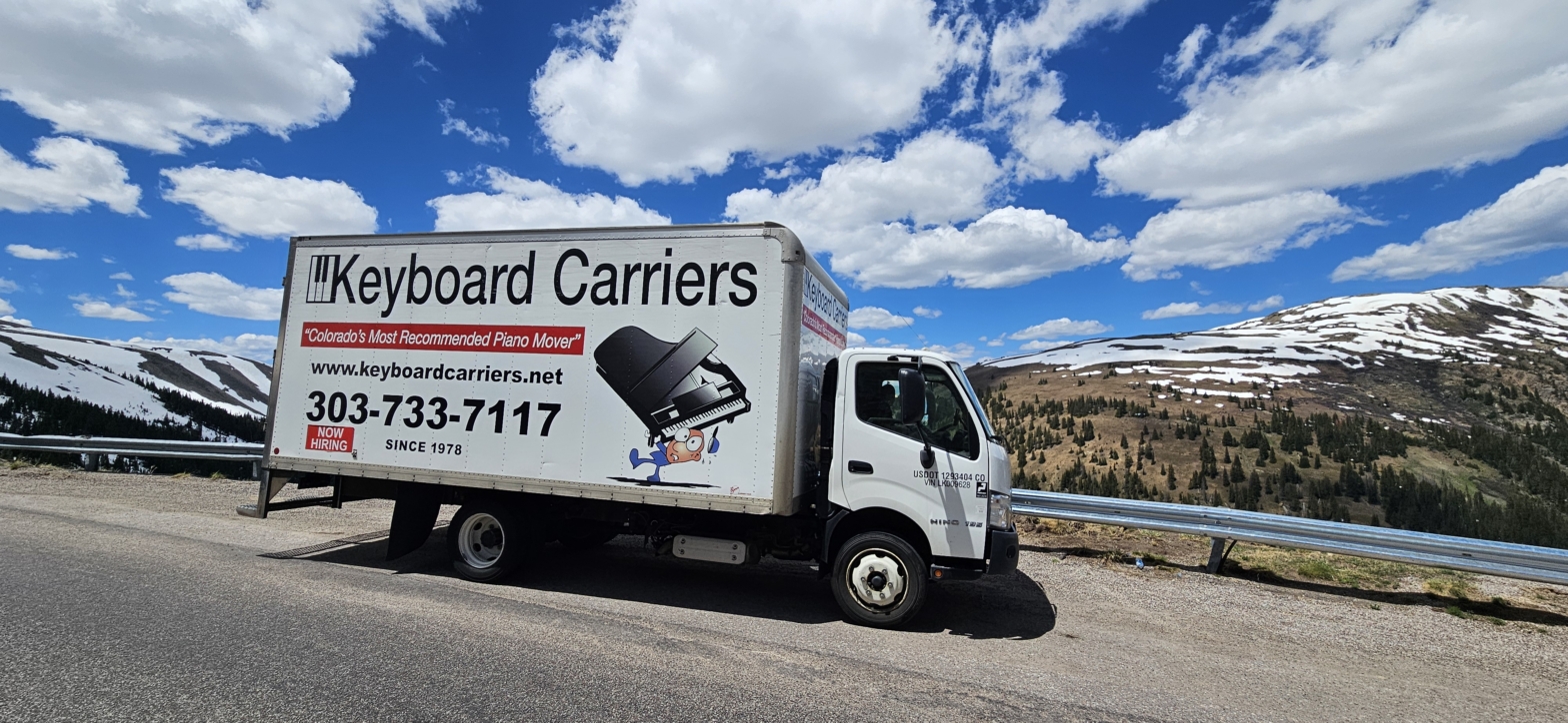 Truck on mountain road with blue sky.
