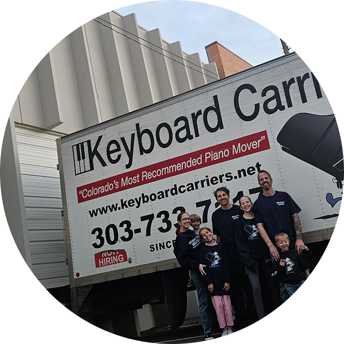 Three people posing in front of a Keyboard Carrier truck.
