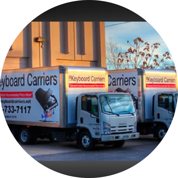 Two white trucks with Keyboard Carriers branding parked outdoors.