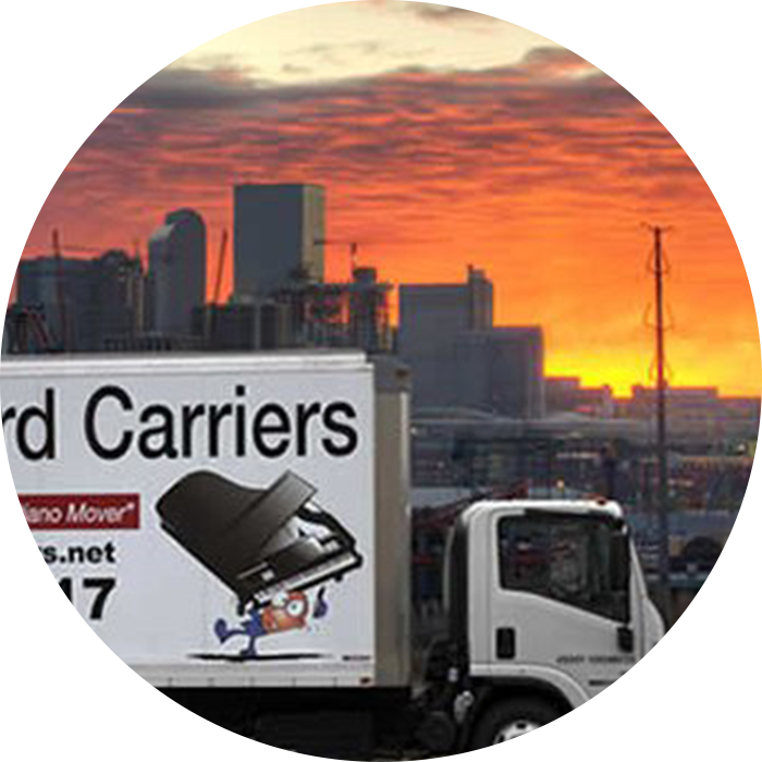 Sunset over a city skyline with a moving truck in the foreground.